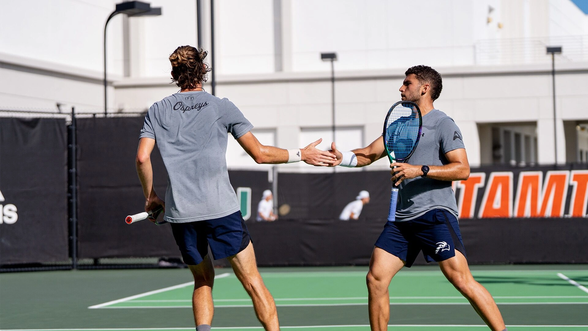 Zwei Tennisspieler geben sich am Netz die Hand