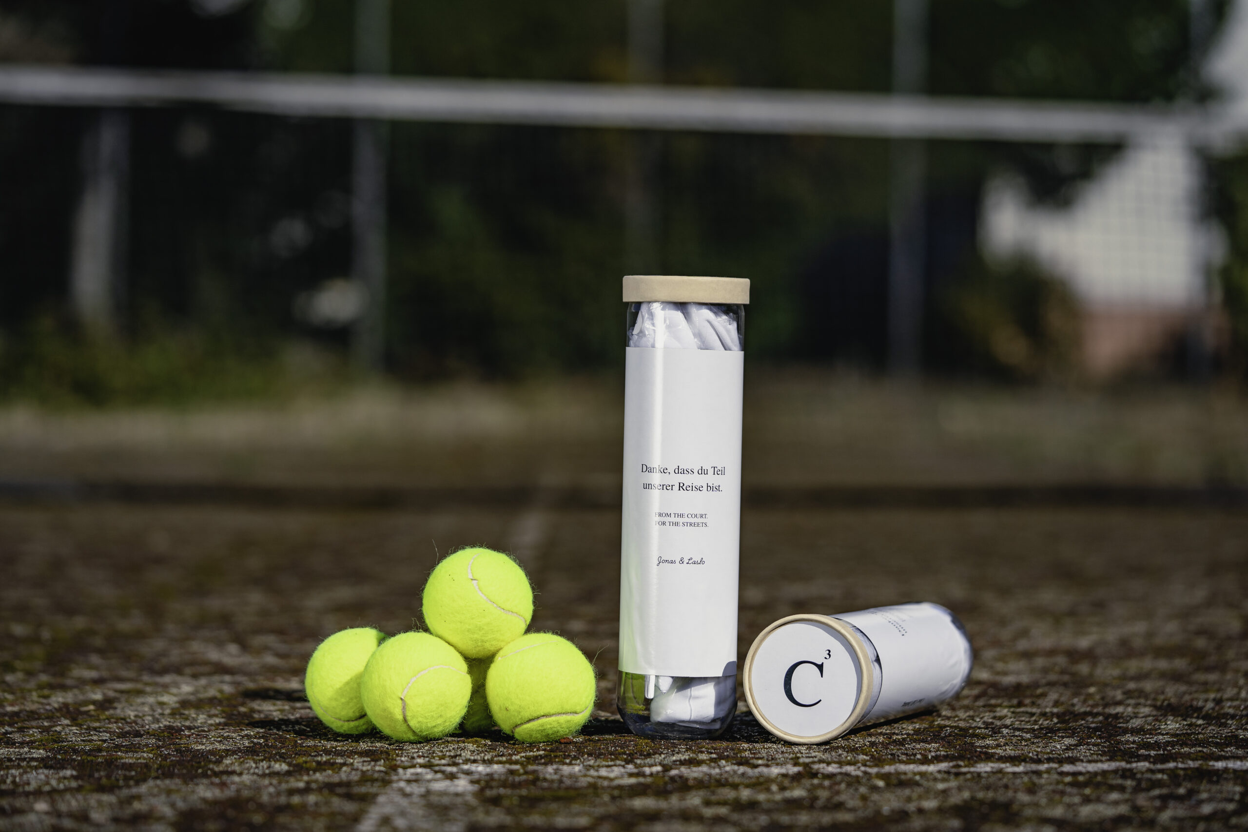 Close Call Clothing Verpackung auf dem Tennisplatz mit Tennisbällen